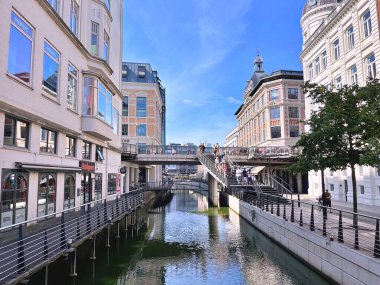 26.08.2025. Aarhus kasabasının şehir merkezindeki Aarhus A nehri boyunca ilerleyin. Mağazalar ve ofisler her iki tarafta, Magasin Alışveriş Merkezi arka planda.