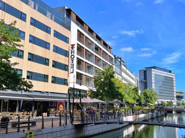 26.08.2025. Aarhus kasabasının şehir merkezindeki Aarhus A nehri boyunca ilerleyin. Mağazalar ve ofisler her iki tarafta, Magasin Alışveriş Merkezi arka planda.