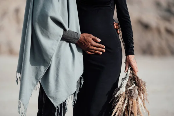 身穿黑色衣服的孕妇拥抱着非洲裔美国男人 一对夫妇在花岗岩峡谷上摆姿势 — 图库照片