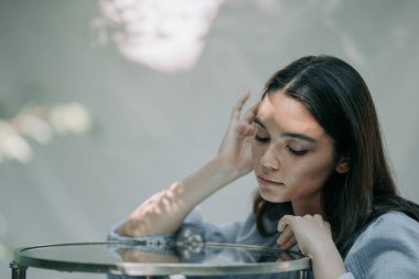 Açık havada dekoratif cam masayla poz veren esmer kızın portresi. 