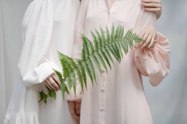  Elbiseli kadınlar kumaşa karşı poz veriyor.