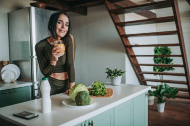 Mutfakta sağlıklı yiyeceklerle poz veren güzel ve sportif bir kadın.