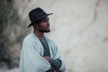 Fötr şapkalı, granit kanyona poz veren Afro-Amerikan bir adamın portresi. 