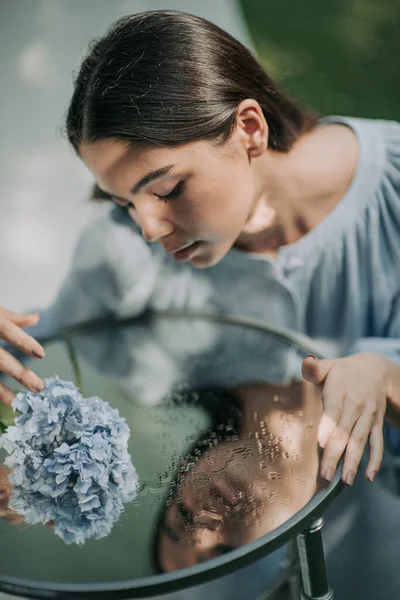 笑容满面的姑娘摆设着装饰玻璃桌子和海德拉花 — 图库照片