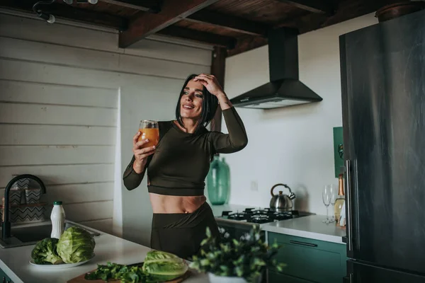 Mutfakta sağlıklı yiyeceklerle poz veren güzel ve sportif bir kadın.