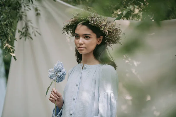 花輪姿の若い女性があじさいの花を手にカメラでポーズをとって — ストック写真