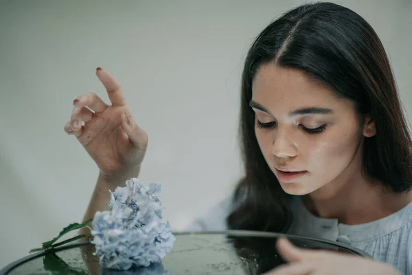 Gadis Ceria Berpose Dengan Meja Kaca Dekoratif Dan Bunga Hydrangea — Stok Foto