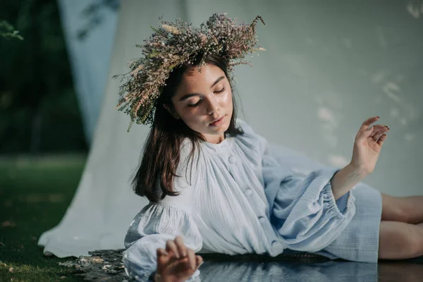 花の花輪の魅力的な女性が公園で鏡を見て — ストック写真