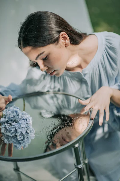 笑容满面的姑娘摆设着装饰玻璃桌子和海德拉花 — 图库照片