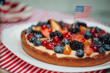 Süslü tatil masasının üzerinde Amerikan bayrağı olan meyveli pasta. 