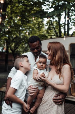 Arka planda karavanla parkta duran mutlu aile portresi.