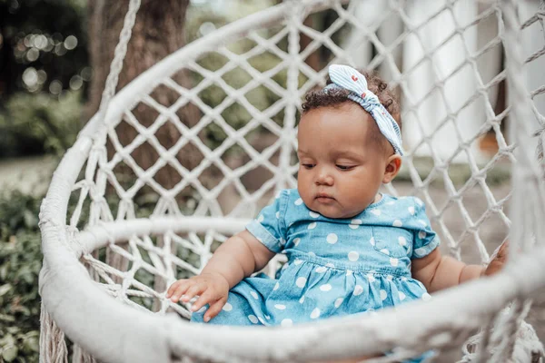 穿着蓝色衣服坐在柳条椅上的可爱小女孩的户外肖像 — 图库照片