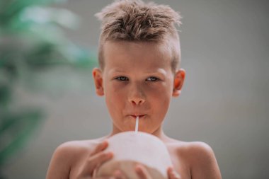 Küçük şirin çocuk yazın hindistan cevizi suyu içiyor. 