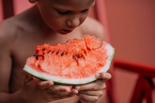 Kleiner Junge Sitzt Auf Dem Roten Stuhl Und Isst Wassermelone — Stockfoto