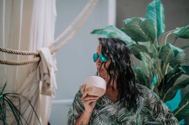 Güneş gözlüklü mutlu kız kokteyl tutuyor.