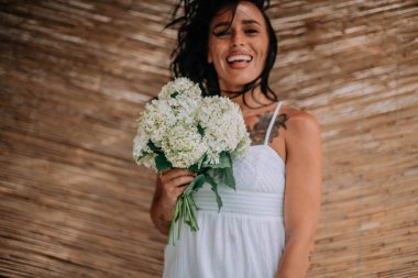 Beyaz elbiseli gelin elinde çiçekler 