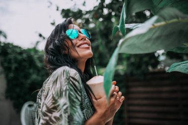 Güneş gözlüklü kadın model kokteyl tutuyor.