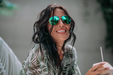 Mutlu esmer kız kokteyl içiyor ve dışarıda takılıyor. 