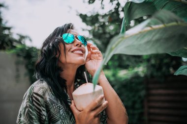 Güneş gözlüklü kadın model kokteyl tutuyor.