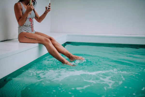 アイスクリームとスマートフォンを持った美しい女性がプールに座って — ストック写真