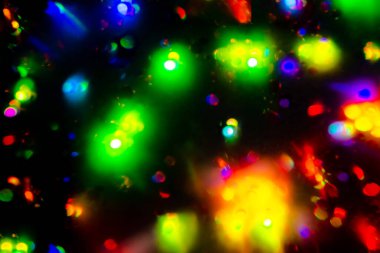 Noel çelengi ışığı. Siyah arkaplanda renkli bokeh bulanık dekor. Kaleydoskop konfeti ışını. Tatil duvar kâğıdı gece partisi parlıyor. Odaklanmış karanlık bir holografik. Bulanık Clipart 'ı özetle