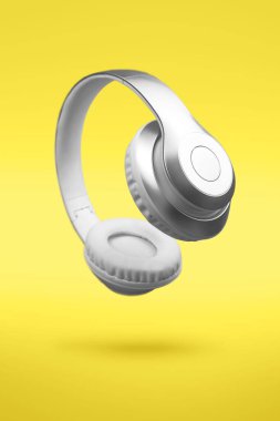Açık sarı arka planda gümüş gri metalik kablosuz kulaklıklar. Yılın 2021 rengi posteri, afiş şablonu. Uçan asgari müzik aygıtı konsepti