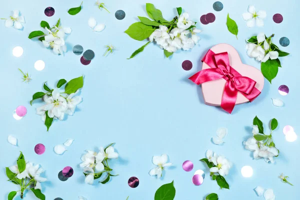 Forma de corazón caja de regalo rosa, floreciendo flores blancas borde sobre fondo azul con plantilla de banner de espacio. — Foto de Stock