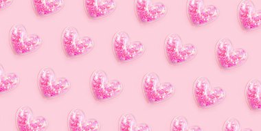 Pastel pembe arka planda parıltılı pek çok kalp. Aşk modeli. Güzel bir karşılama günü, mutlu yıllar bayram dekoru. Parlak romantik duvar kağıdı süsü.