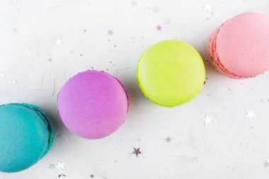 Parlak gri beton arka planda parlak konfeti dekorlu renkli Makaron üst görünümü. Fransız lezzetli fırın gurme tatlıları. Minimum bayram pastel tatlı, lezzetli bademli bisküvi