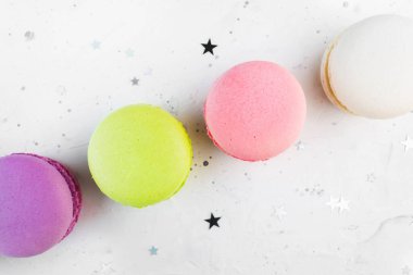 Renkli badem kurabiyesi yıldız konfeti dekoru olan beyaz arka planda üst görüntüyü kapat. Lezzetli bademli kurabiyeler. Fransız lezzetli makarna gurmesi tatlısı. Makro atış