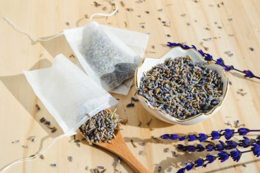 Ahşap masada kurutulmuş lavanta, kaşık ve çay poşeti. Organik bitkisel içecek. Sıfır atık paketi.