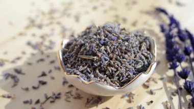 Ahşap masada dönen lavanta çiçekli porselen kâse. Kuru içerik videoyu döndürür
