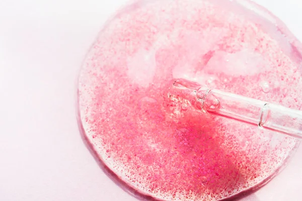 Pembe serum, kozmetik sıvısı ve parlak arka plan makro manzaralı pipet. Şeffaf güzellik ürünü peptidler, seramikler, hyaluron jel kumaşı. Cam düşürücü sıvı makyaj konsepti.