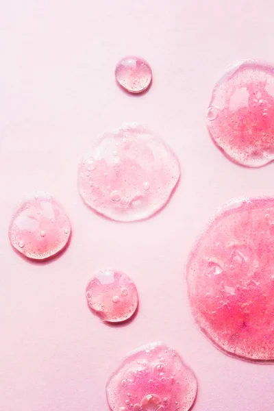 Många Transparenta Kosmetika Droppar Makro Isolerad Ljus Rosa Bakgrund Hudvårdsskrubb — Stockfoto