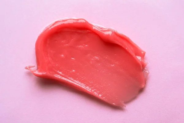 Pink cosmetics smear isolated on pink background. Skincare creme, mask, lipstick or lip gloss swatch. Beauty macro texture. Cosmetic swatch. Liquid makeup product closeup.