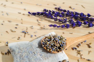 Dried lavender, spoon and tea bag sachet on wooden table. Organic flower herbal drink. Handmade zero waste wrapper. Essential aromatic plant beverage ingredient. clipart