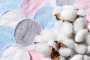 Kozmetik yıkanabilir pastel renkli pamuklu süngerler beyaz arka planda torbaya konur. Doğal temizlik, makyaj yastığı ve kurumuş pamuk. Kumaş cilt bezi. Güzellik sıfır atık kavramı.