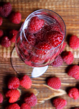 Raspberries in a glass on the wooden background