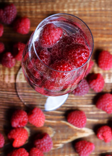 Raspberries in a glass on the wooden background — Zdjęcie stockowe