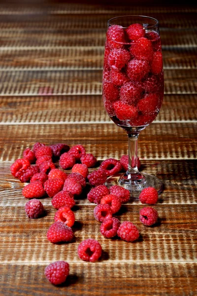 Raspberries in a glass on the wooden background — Zdjęcie stockowe