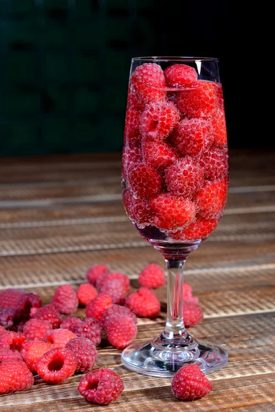 Raspberries in a glass on the wooden background — Stok fotoğraf