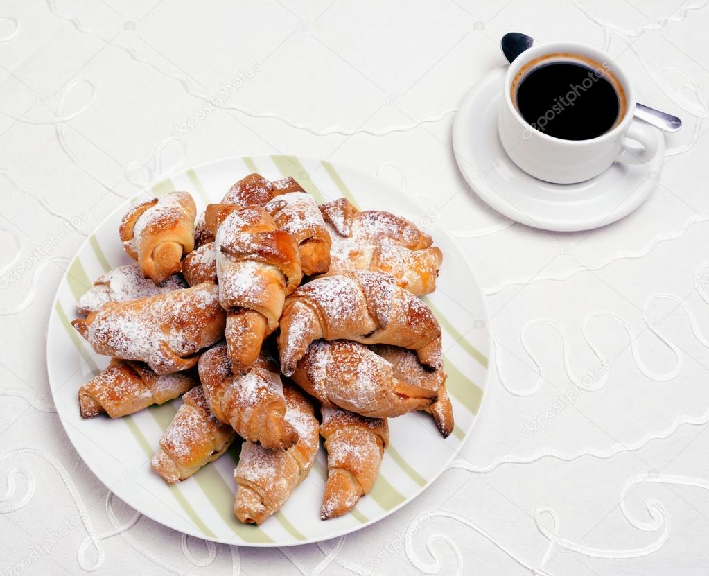 Continental breakfast with croissant and black coffee.