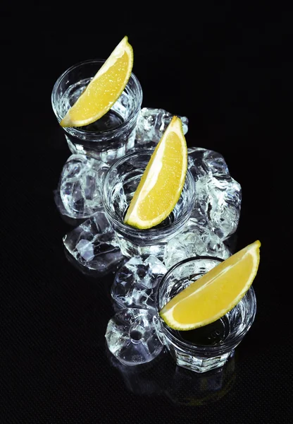 Vodka with lime on black background.