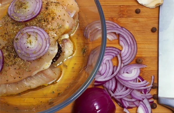 Raw chicken with onion in casserole dish 