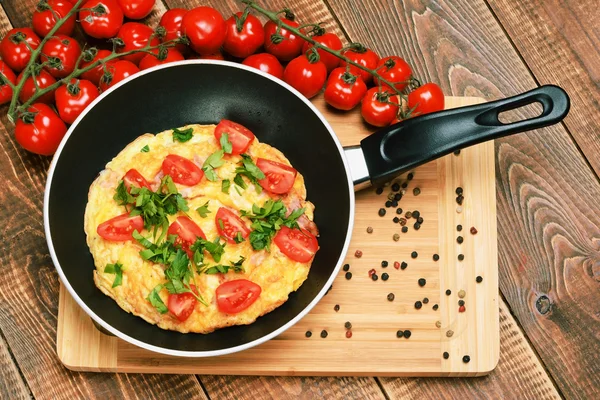 Omelette con prosciutto, pomodori e formaggi sulla padella . — Foto Stock