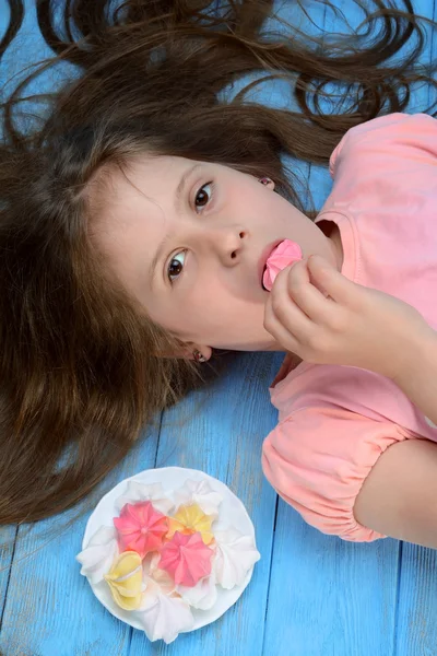 Kız ve mavi arka plan üzerinde renkli Fransız vanilya kremalı kurabiye.