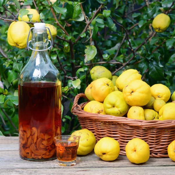Tentür, ayva ve ahşap bir masa üzerinde hasır sepet meyve.