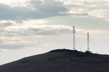 Gökyüzündeki bulutlara karşı tepe üzerinde cep telefonu kulesi