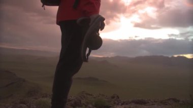 Fotoğrafçı silueti dağlarda duruyor ve birkaç dakika sonra gün batımında kamerayla çekim yapıyor.