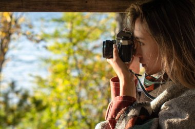 Güzel fotoğrafçı kadın doğadaki bir kamerada fotoğraf çekiyor.